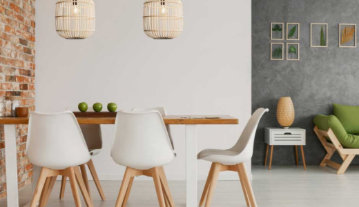 Table de cuisine en bois entourée de chaises avec dossier blanc, deux luminaires aux teintes naturelles