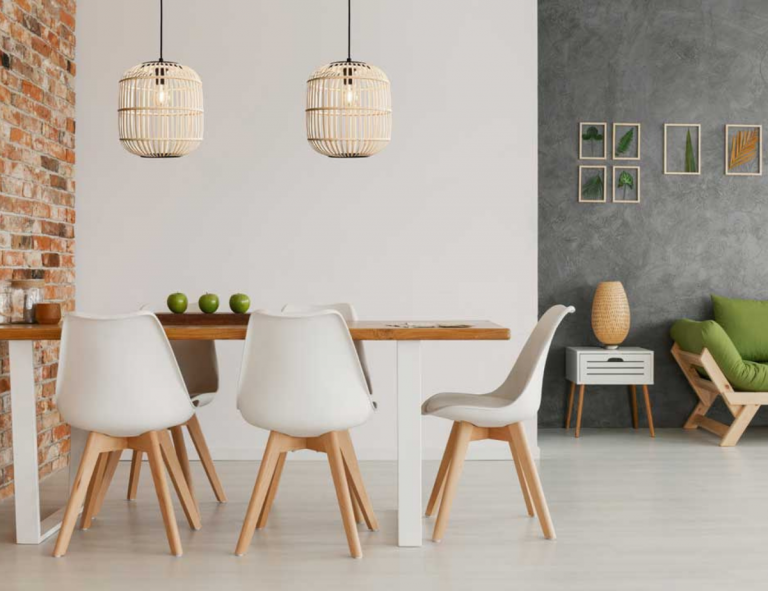 Table de cuisine en bois entourée de chaises avec dossier blanc, deux luminaires aux teintes naturelles